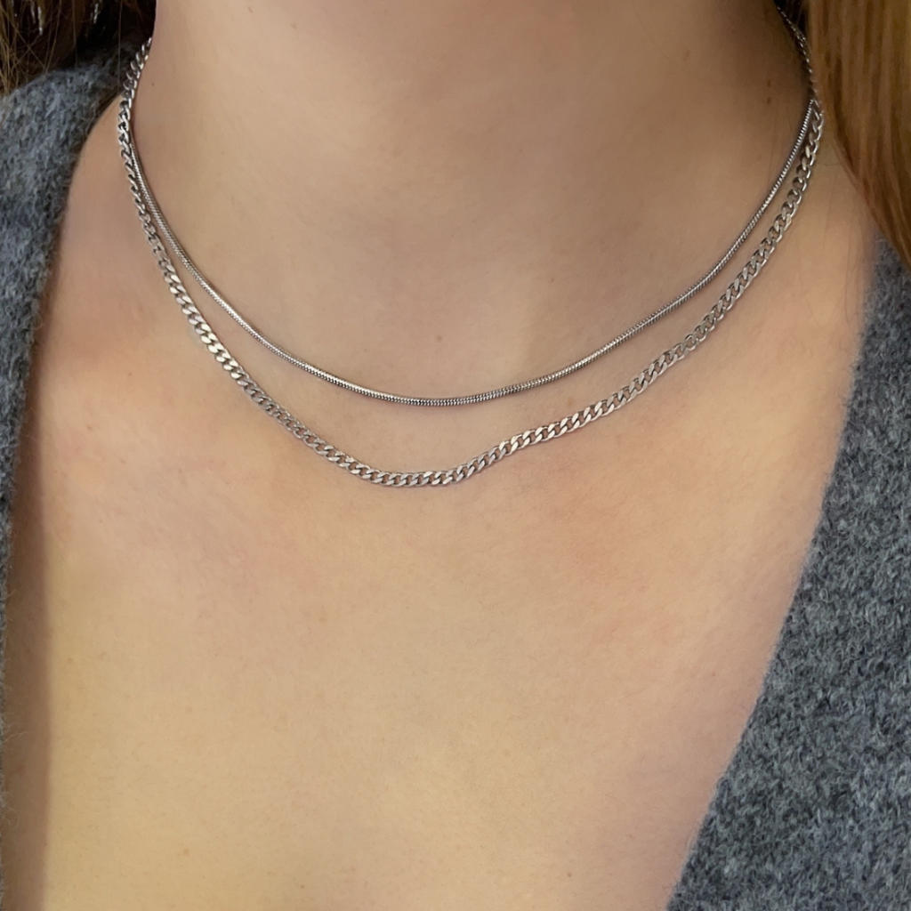 Snake and cuban chain necklaces layered together on a model